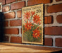 A vintage-style postage stamp featuring a vibrant illustration of red cactus flowers is displayed on a brick wall.