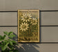 a postage stamp with a floral design, mounted on a wall next to a plant.