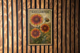 A postage stamp featuring a large, vibrant flower is displayed on a wooden wall.