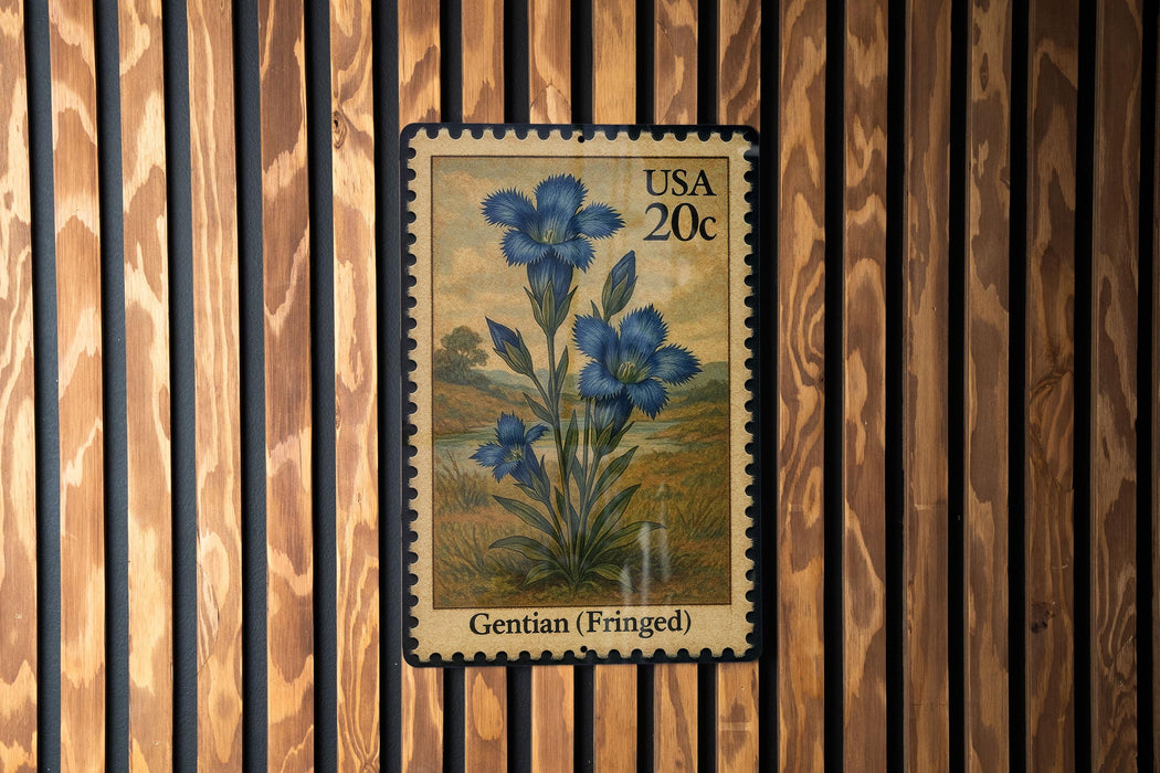 A postage stamp featuring a blue flower, labeled as a Gentian (Fringed) flower, is displayed on a wooden wall.