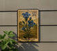 A postage stamp featuring a blue flower is displayed on a wall, with a plant to the left.