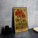 A vintage-style postage stamp featuring a vibrant illustration of geranium flowers, placed on a dark surface next to some black camera lenses.