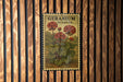 A vintage-style poster of geranium flowers is displayed on a wooden wall, with the word "GERANIUM" written on it.