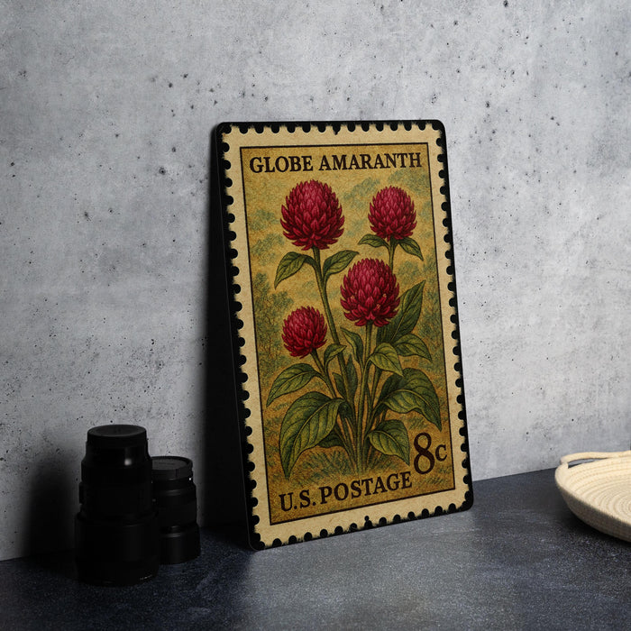 A vintage-style postage stamp featuring a floral design with red flowers, placed on a dark surface next to some black camera lenses.