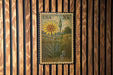 A US postage stamp featuring a yellow flower and green foliage, mounted on a wooden wall.