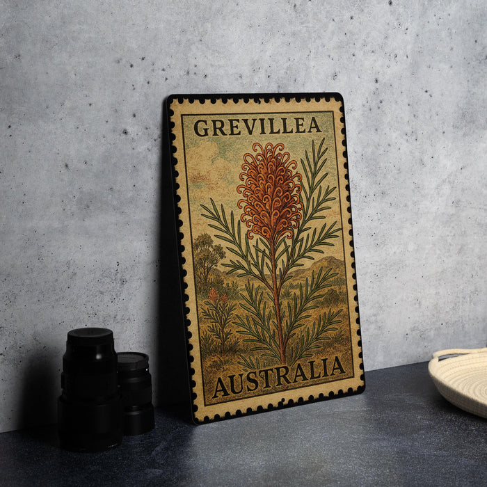 A framed metal stamp with a floral design and text, placed on a countertop next to some black camera lenses.