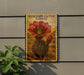 A framed illustration of a cactus flower is displayed on a wall, with a plant in the foreground.