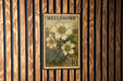 A vintage-style postage stamp from Hellebore, featuring a floral illustration of a white flower with green leaves, mounted on a wooden wall.
