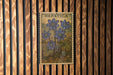 a framed illustration of blue flowers on a wooden wall.