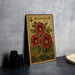 A framed print of a red flower with green leaves is displayed on a gray wall, accompanied by a stack of black camera lenses and a white dish.