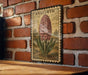 A vintage-style illustration of a hyacinth flower is displayed on a brick wall, mounted on a wooden surface.