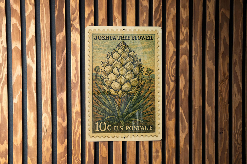 A 10c U.S. postage stamp featuring a Joshua tree flower is displayed on a wooden wall.