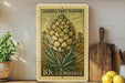 A vintage-style postage stamp featuring a Joshua tree flower, placed on a shelf next to a wooden cutting board and some potted plants.
