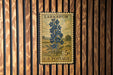 A vintage U.S. postage stamp from Larkspur, featuring a blue flower illustration, is displayed on a wooden wall.