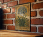 A vintage-style metal stamp depicting a lily of the Nile flower is displayed on a brick wall.