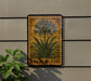 a wooden sign with a floral illustration of a lily of the Nile plant, mounted on a wall next to a plant.