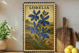 A framed stamp depicting blue flowers is displayed on a shelf next to a wooden cutting board and a potted plant.