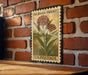 A vintage-style postage stamp featuring a milkweeds (swamp) plant, mounted on a brick wall.
