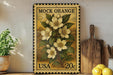 A vintage-style postage stamp featuring a floral design, placed on a wooden surface next to a potted plant and kitchen utensils.