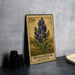 A metal stamp featuring a depiction of blue flowers, likely a Monkshood acontum, is displayed on a table next to some black camera lenses.
