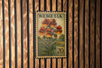 A vintage-style postage stamp from Nemeria, featuring a floral design with red and orange flowers, is displayed on a wooden wall.