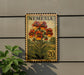 A postage stamp featuring a colorful illustration of flowers, with the word "NEMESIA" printed on it. The stamp is mounted on a wall, and there is a plant next to it.