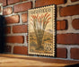 A vintage-style postage stamp featuring a cactus plant on a brick wall.