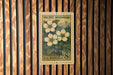 A U.S. postage stamp featuring a floral design is displayed on a wooden wall.