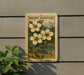 A wooden sign with a postage stamp design hangs on a wall, featuring a depiction of a plant with yellow flowers.