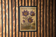 A framed image of a pasque flower is hanging on a wooden wall.
