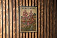 A framed print of a penstemon flower is displayed on a wooden wall.