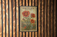 A vintage-style postage stamp featuring a floral illustration of moss roses, mounted on a wooden wall.