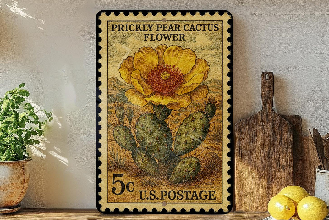A framed postage stamp depicting a Prickly Pear Cactus flower, with a 5 cent value, is displayed on a shelf next to a wooden cutting board and a potted plant.