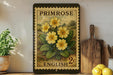 A vintage-style postage stamp featuring yellow flowers is displayed on a shelf, accompanied by a wooden cutting board, a potted plant, and some lemons.