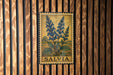 A framed illustration of blue flowers is hanging on a wooden wall.