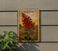 a framed illustration of a red flower on a wall, with a plant next to it.