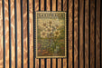 a framed illustration of a flower on a wooden wall.