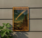 A wooden postage stamp depicting a shooting star against a night sky with mountains and pine trees.