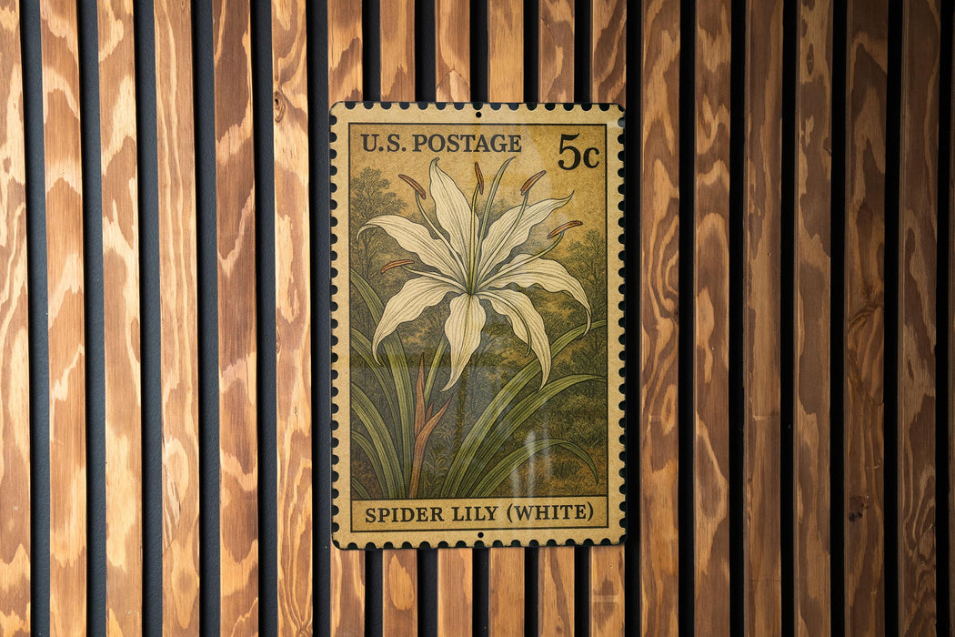 A U.S. postage stamp featuring a white spider lily plant is displayed on a wooden wall.