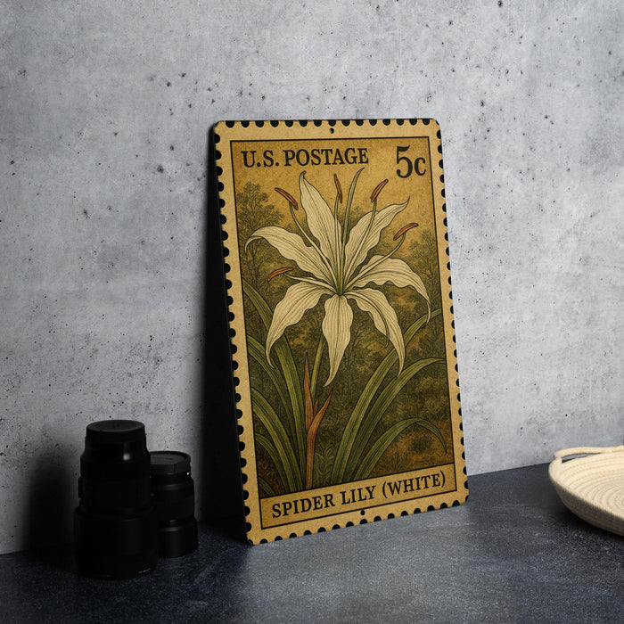 A U.S. postage stamp featuring a white lily flower, placed on a gray surface next to some black camera lenses.