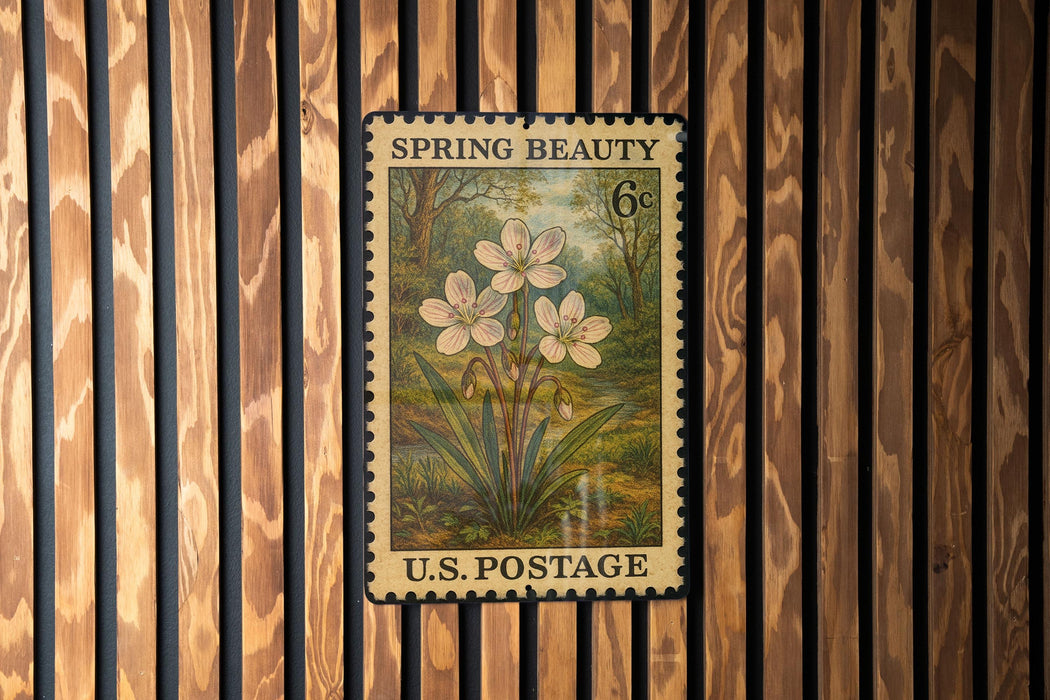 A vintage U.S. postage stamp featuring a floral design is displayed on a wooden wall.