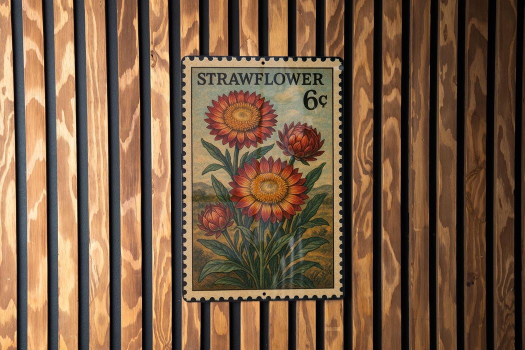 A vintage-style stamp depicting a flower with the text "STRAWFLOWER 6c" on it, hanging on a wooden wall.