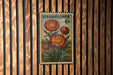 A vintage-style stamp depicting a flower with the text "STRAWFLOWER 6c" on it, hanging on a wooden wall.