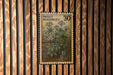 A vintage-style postage stamp featuring a floral illustration is displayed on a wooden wall.