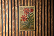 A 5c postage stamp featuring a red flower and green leaves, mounted on a wooden wall.