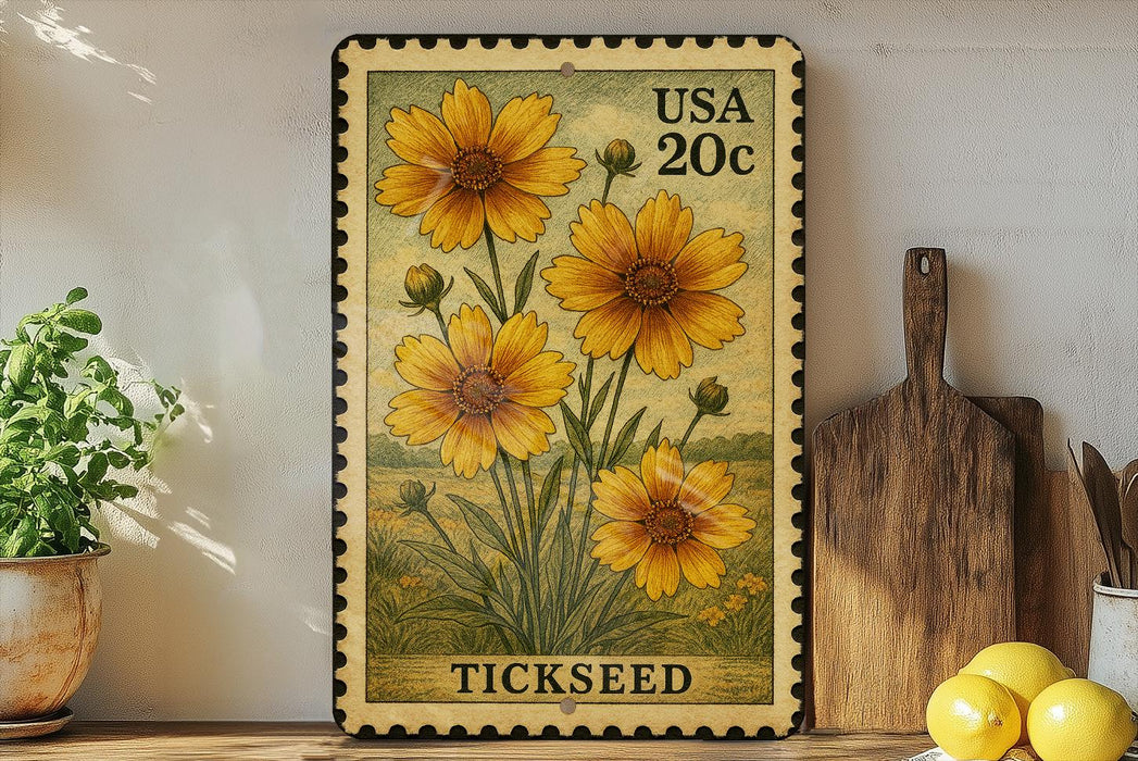 A framed postage stamp featuring a vibrant illustration of yellow flowers, with the word "TICKSEED" printed below. The stamp is placed on a wooden shelf next to a wooden cutting board and a potted plant.