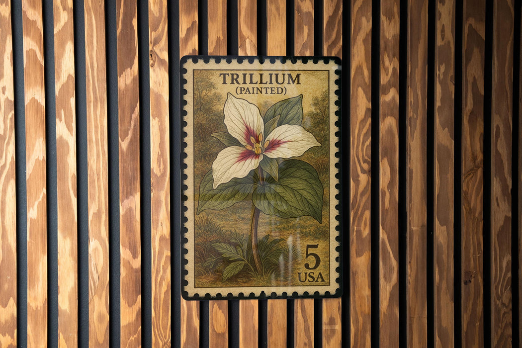 A postage stamp featuring a painted Trillium flower, which is a type of wildflower, mounted on a wooden background.