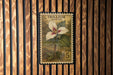 A postage stamp featuring a painted Trillium flower, which is a type of wildflower, mounted on a wooden background.
