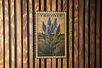 a framed illustration of blue flowers on a wooden wall.
