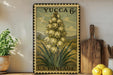 A vintage postage stamp featuring a tall flower with yellow petals, displayed on a shelf next to a wooden cutting board and a potted plant.